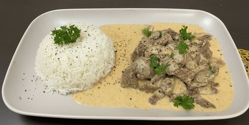 Plated dish of creamy mushroom sauce with a side of white rice on a gray surface.